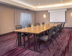Sonesta Select Allentown Bethlehem Airport meeting room, including long wooden table, projector screen, seating for eight, and window.