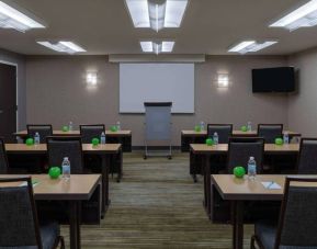 Hotel meeting room, with tables arranged in a classroom format, facing a lectern, TV, and whiteboard.