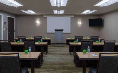 Hotel meeting room, with tables arranged in a classroom format, facing a lectern, TV, and whiteboard.