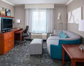 Sonesta Select Boston Lowell Chelmsford guest room lounge, furnished with sofa, chair, and TV.