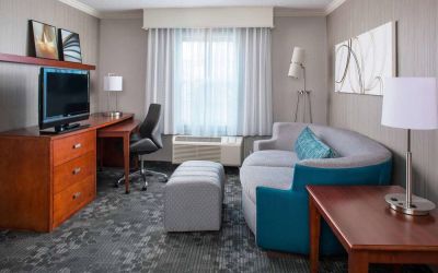 Sonesta Select Boston Lowell Chelmsford guest room lounge, furnished with sofa, chair, and TV.