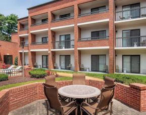 The hotel patio is close to the rooms, and has a circular table surrounded by a quintet of chairs.