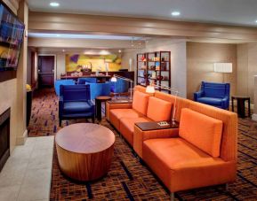The hotel’s lobby lounge is furnished with armchair and sofa seating, coffee tables, a large television, and a fireplace.
