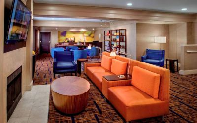 The hotel’s lobby lounge is furnished with armchair and sofa seating, coffee tables, a large television, and a fireplace.