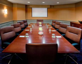 Sonesta Select Boston Danvers meeting room, with ten swivel chairs around a long table, and a projector screen.