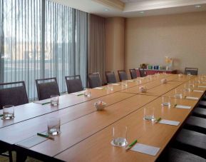 Hotel meeting room, with long wooden table, seating for over a dozen attendees, and large windows.