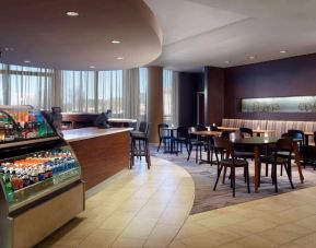 Sonesta Select Atlanta Cumberland Galleria’s dining area features a bar, both tall stool and table seating, and large windows.