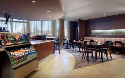 Sonesta Select Atlanta Cumberland Galleria’s dining area features a bar, both tall stool and table seating, and large windows.