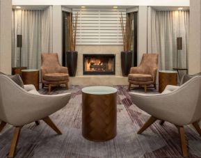 Sonesta Select Seattle Bellevue Redmond’s lobby includes coffee tables and comfy chairs close to a fireplace.