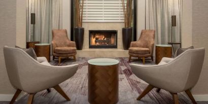 Sonesta Select Seattle Bellevue Redmond’s lobby includes coffee tables and comfy chairs close to a fireplace.