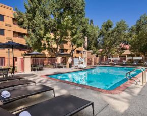 The outdoor pool at Sonesta Select San Jose Airport features a lift, and has nearby sun loungers and shaded tables and chairs.