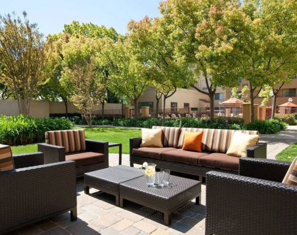 The hotel’s patio has trees nearby, and a mix of sofa and armchair seating.