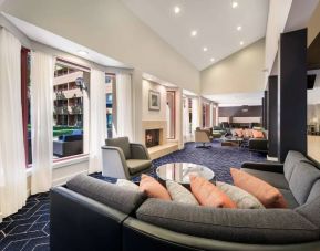 Sonesta Select San Jose Airport’s lobby lounge is furnished with armchairs and sofa seating, coffee tables, and a fireplace.