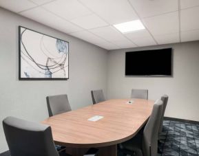 Hotel meeting room, with half a dozen chairs set around a wooden table, and a large TV on the wall.