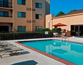 Sonesta Select Charlotte University Research Park’s outdoor pool has sun loungers and a shaded table and chairs by the side.