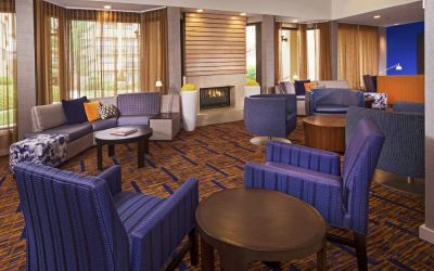 Sonesta Select Charlotte University Research Park’s lobby is furnished with a fireplace, large windows, coffee tables, and comfortable seating.