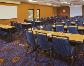 Hotel meeting room, featuring tables arranged in a classroom style facing a projector screen, with a whiteboard to one side.