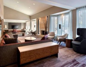 The lobby lounge in Sonesta Select Boston Milford includes chairs, sofas, and coffee tables, plus large windows.