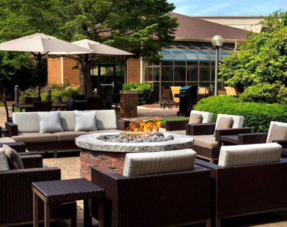 The hotel’s fire pit is surrounded by sofas and armchairs, and plenty of coffee tables, with pleasant greenery in the background.