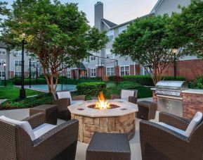 Sonesta ES Suites Baltimore BWI Airport’s fire pit is surrounded by armchairs and coffee tables, with a barbecue conveniently close.