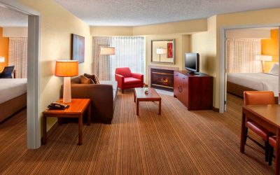 Double bed guest room in Sonesta ES Suites Allentown Bethlehem Airport, including lounge with sofa, TV, armchair, and fireplace.
