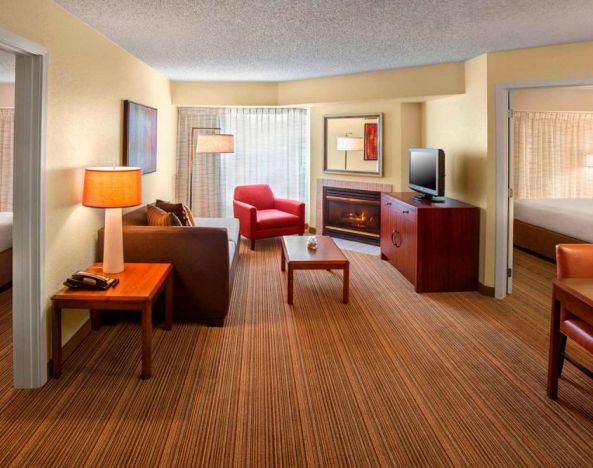 Double bed guest room in Sonesta ES Suites Allentown Bethlehem Airport, including lounge with sofa, TV, armchair, and fireplace.