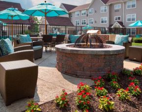 Sonesta ES Suites Allentown Bethlehem Airport’s fire pit has armchairs arranged around it, with the pool and a flowerbed nearby.