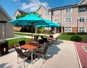 Sonesta ES Suites Allentown Bethlehem Airport’s patio is furnished with shaded tables and chairs.