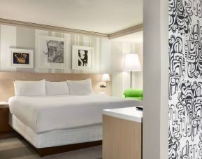 King bed guest room in Royal Sonesta Minneapolis Downtown, featuring art on the wall and a bedside armchair.