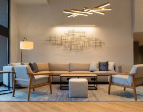 Sonesta Silicon Valley’s lobby is furnished with a comfortable sitting area, with long sofa, chairs, and multiple coffee tables.