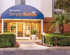 Sonesta Simply Suites Irvine East Foothill’s exterior features a covered entranceway, clear signage, and pleasant greenery.