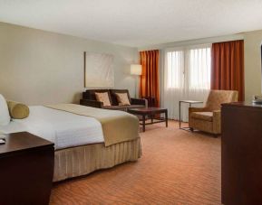 Sonesta Miami Airport double bed guest room, furnished with armchair, sofa, and window.