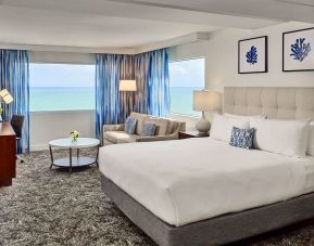 Sonesta Fort Lauderdale Beach double bed guest room, featuring ocean views, a sofa, coffee table, and workspace.