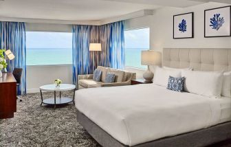 Sonesta Fort Lauderdale Beach double bed guest room, featuring ocean views, a sofa, coffee table, and workspace.