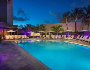 Sonesta Fort Lauderdale Beach’s outdoor pool has palm trees and sun loungers by the side, with shade available.