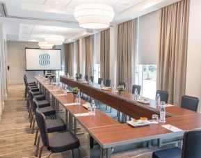 Sonesta Fort Lauderdale Beach meeting room, with a head table for one person and two long tables each with space for 10 attendees, and a projector screen.