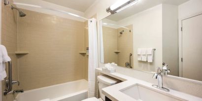 Guest bathroom with shower and bath at Sonesta Simply Suites Detroit Warren.