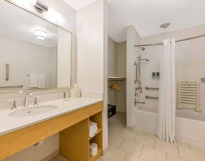 Guest bathroom in Sonesta ES Suites Charlotte Arrowood, furnished with large mirror, sink, bath and shower.