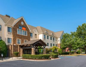 The hotel’s exterior has a pleasant abundance of greenery, including numerous trees, a covered entrance, and parking spaces.