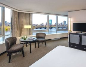 Royal Sonesta Boston double bed guest room, featuring wonderful city views, a widescreen TV, two chairs, and a coffee table.