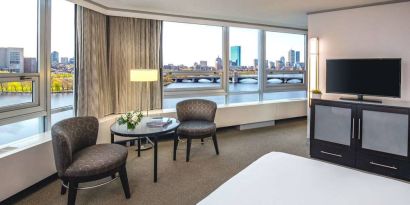 Royal Sonesta Boston double bed guest room, featuring wonderful city views, a widescreen TV, two chairs, and a coffee table.
