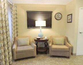 Sonesta Simply Suites Chicago Waukegan’s lobby is furnished with two armchairs, a coffee table, and a window.