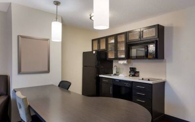 Sonesta Simply Suites Des Moines guest room kitchen, including oven, hob, microwave, fridge-freezer, and a breakfast table.