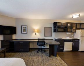 Sonesta Simply Suites Des Moines guest room, furnished with bed, kitchenette, TV, and workspace desk and chair.