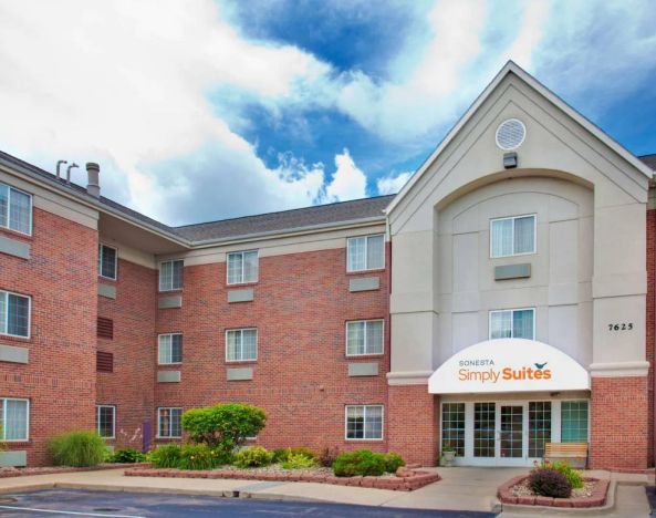 Sonesta Simply Suites Des Moines’ exterior has pleasant greenery, parking, and red brick architecture.
