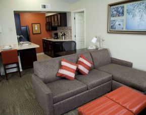 Sonesta ES Suites Sunnyvale guest room living area featuring a corner sofa, with nearby kitchenette and breakfast bar.