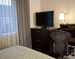 Sonesta ES Suites Sunnyvale guest room workspace, including desk, chair, and lamp, with nearby TV.
