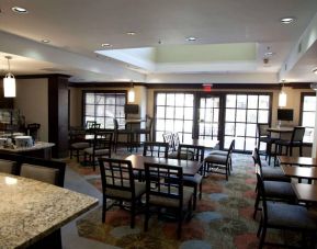 Sonesta ES Suites Sunnyvale’s dining lounge is furnished with tables for two to four diners, a mix of regular and tall stool seating, large windows, and multiple televisions.