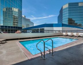 Sonesta Los Angeles Airport LAX’s outdoor pool has loungers by the side and towering buildings nearby.