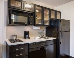 Sonesta Simply Suites Dallas Galleria guest room kitchen, furnished with fridge-freezer, hob, oven, and microwave.